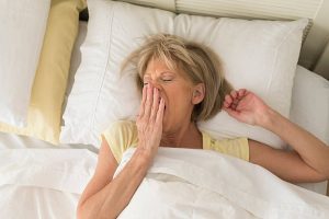 Woman struggling to sleep in her caravan bed because she is struggling with menopausal night sweats
